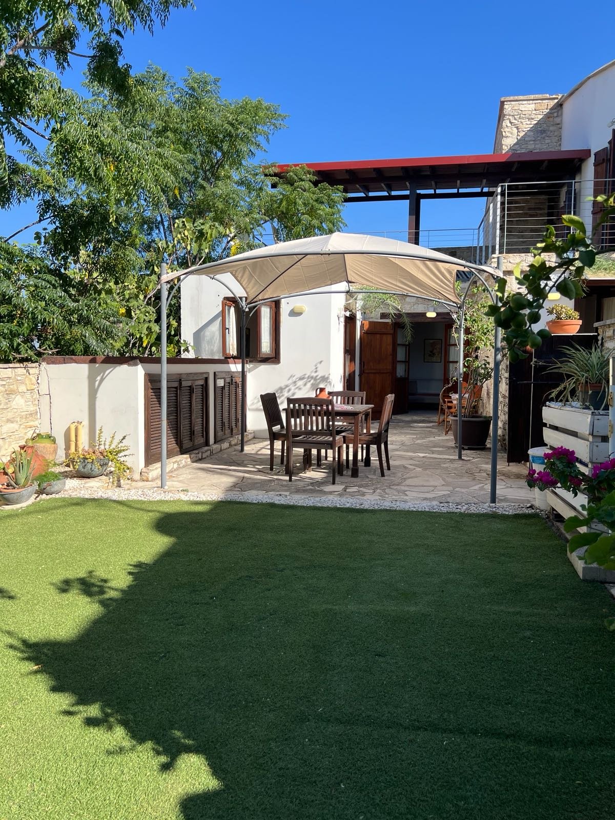 The garden lawn and a shaded table on the stone courtyard, with the house behind